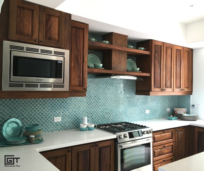 A kitchen with brown cabinets, white countertops, and a wall with scale cement tile