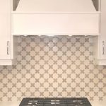 A white and gray kitchen with a stainless steel stove top