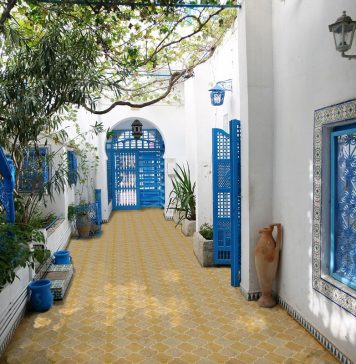 outdoory patio with yellow and beige titles with blue doors and staircase