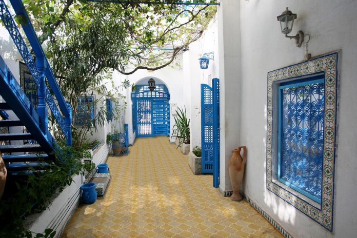 outdoory patio with yellow and beige titles with blue doors and staircase